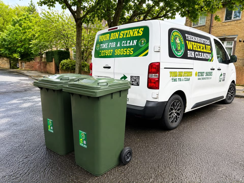 The BinBusters branded van parked on a residential street beside two clean green wheelie bins