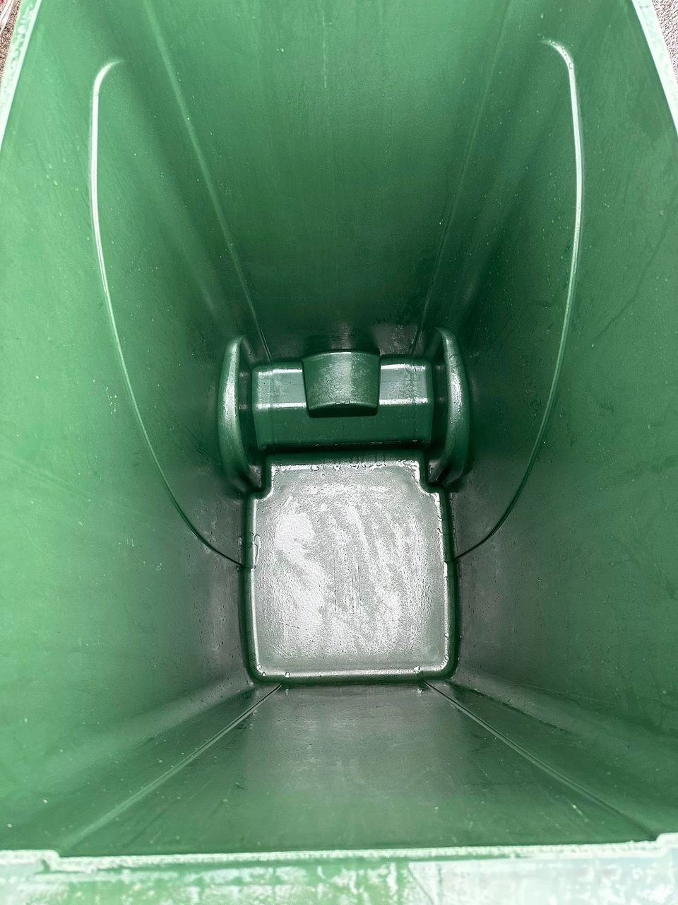 Spotless interior of the same green wheelie bin after a professional clean