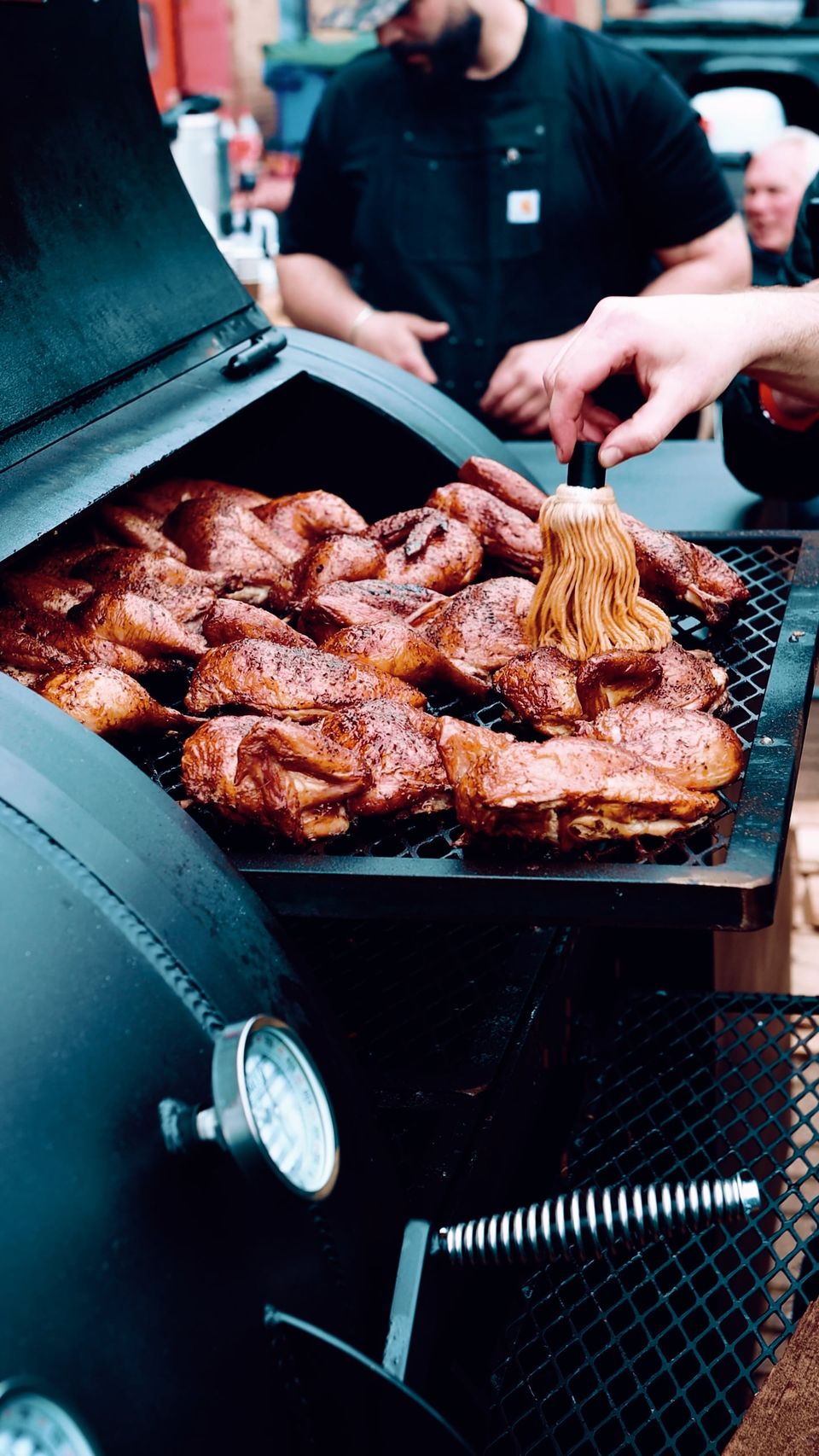 Pitmaster basting chicken on the Wilson's BBQ smoker