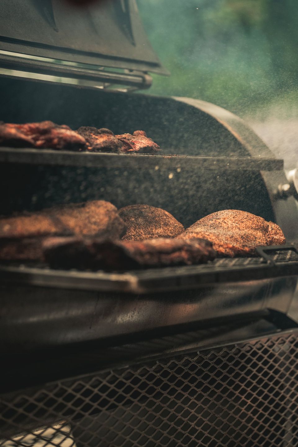 Smoke rolls from an open Wilson's BBQ smoker with ribs and brisket inside