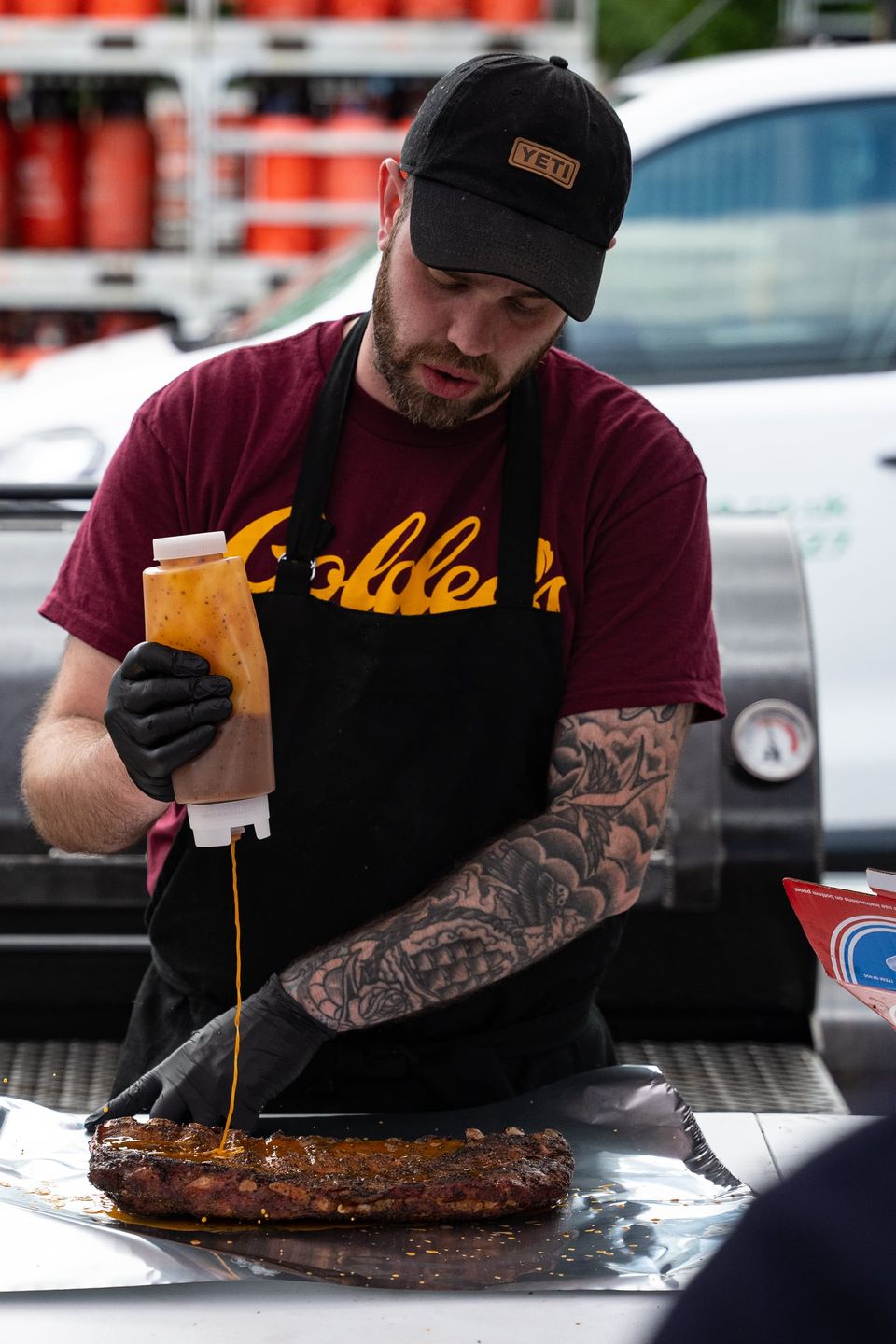 Pitmaster saucing ribs with a squeeze bottle at a Wilson's BBQ class