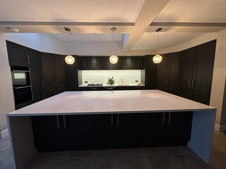 Modern kitchen with dark cabinets and white quartz island in completed extension